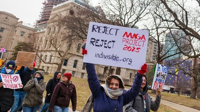 Un demonstrant ține o pancartă pe care scrie „Respingeți «proiectul MAGA 2025»”, în timpul unui protest anti-Trump la Reședința de Stat din Indiana, Indianapolis