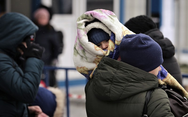 O mamă cu copilul pe umăr aşteaptă să treacă de vamă