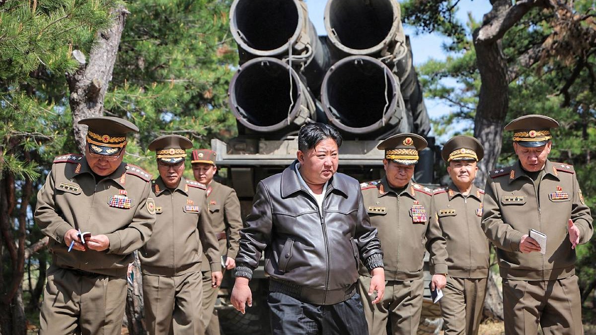 O fotografie furnizată de agenția de știri de stat nord-coreeană KCNA pe 9 mai 2025 îl arată pe liderul Kim Jong-un (centru) vorbind cu oficiali militari în timp ce supraveghează un exercițiu comun de atac care implică artilerie cu rază lungă de acțiune și o nouă variantă de rachete balistice tactice pe frontul de est.
