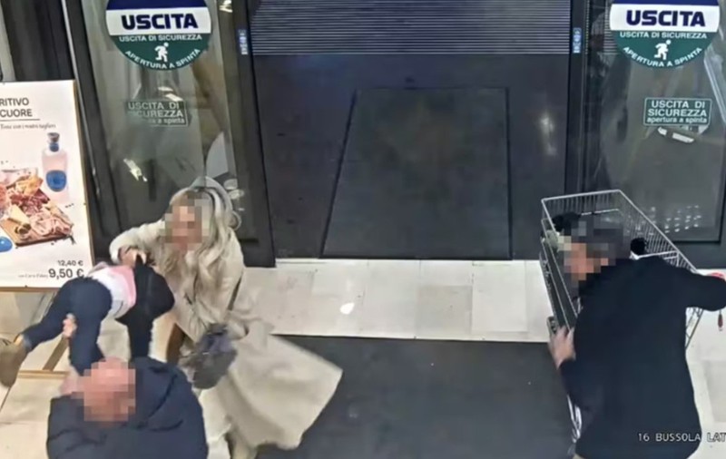 Imaginea, surprinsă de o cameră de supraveghere la ieșirea dintr-un magazin, arată un bărbat care ridică brusc un copil mic, în timp ce o femeie intervine imediat pentru a-l opri.