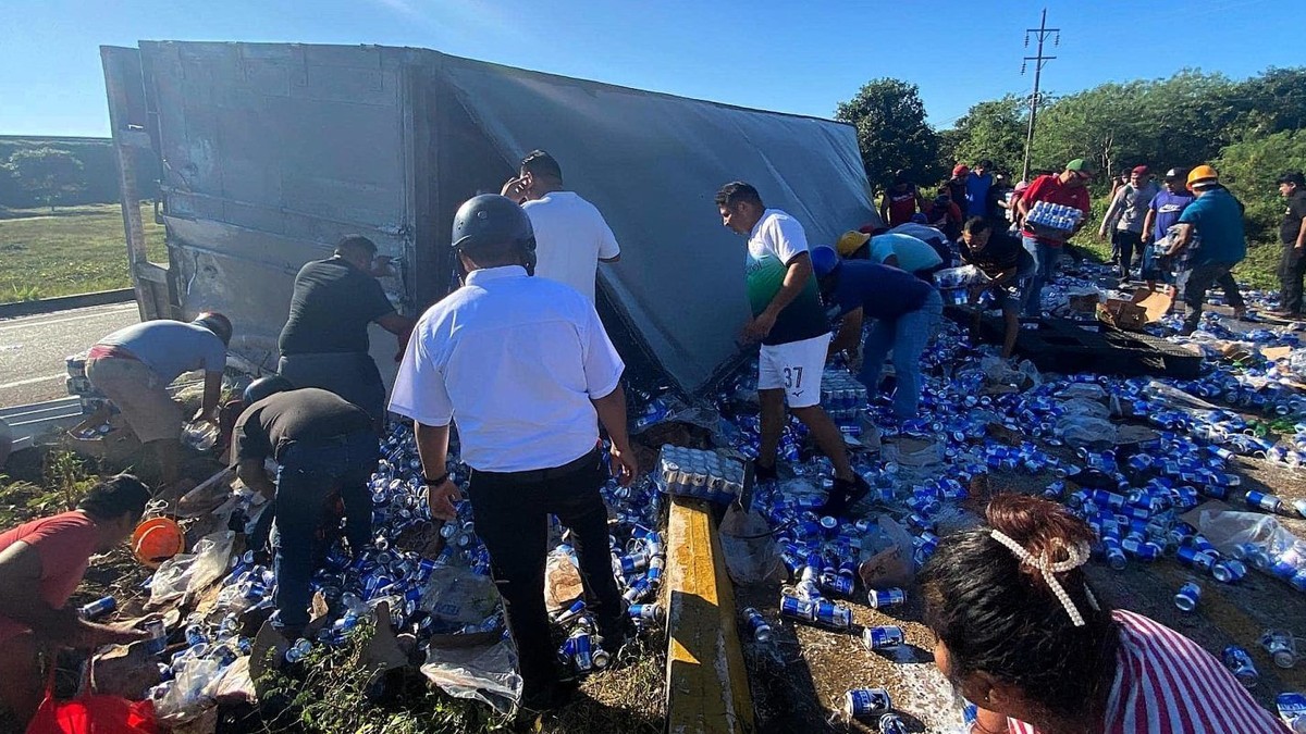 Camion răsturnat. Oamenii privesc la cutiile cu băutură