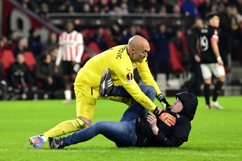 epa10486474 A pitch invader assaults Sevilla FC goalkeeper Marko Dmitrovic during the UEFA Europa league play-off soccer match between PSV Eindhoven and Sevilla FC, in Eindhoven, Netherlands, 23 February 2023. EPA-EFE/OLAF KRAAK