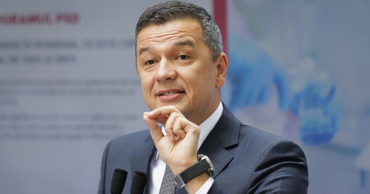 Președintele PSD, Sorin Grindeanu, îmbrăcat cu un sacou gri explică ceva și arată cu mâna, având trei degete lipite, 22 octombrie 2025