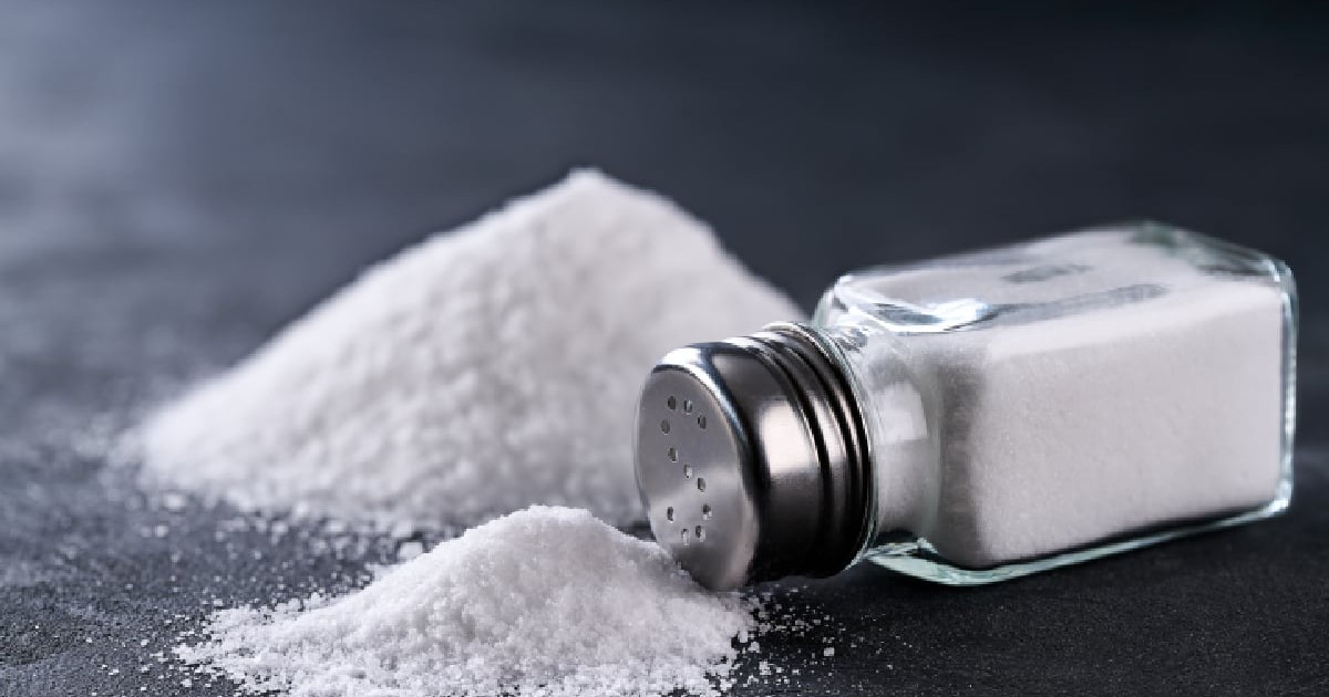 Recipient de sare vărsat pe o masă neagră, iar în jurul lui sunt două grămăjoare de sare