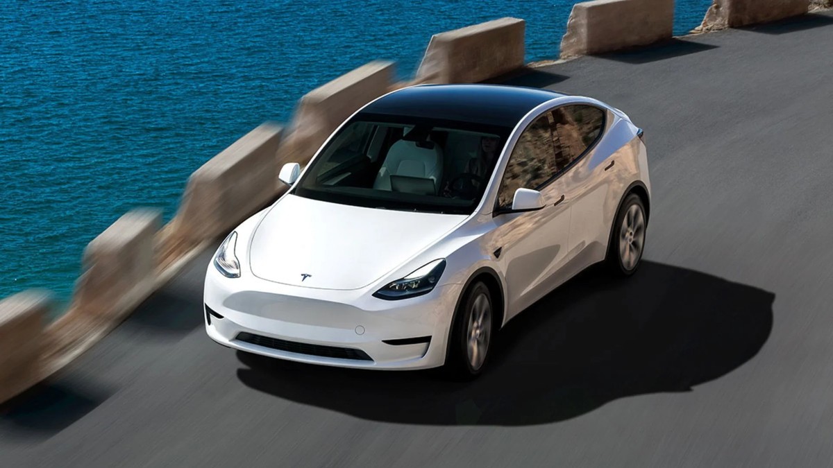 Tesla Model Y alb pe o șosea de lângă mare