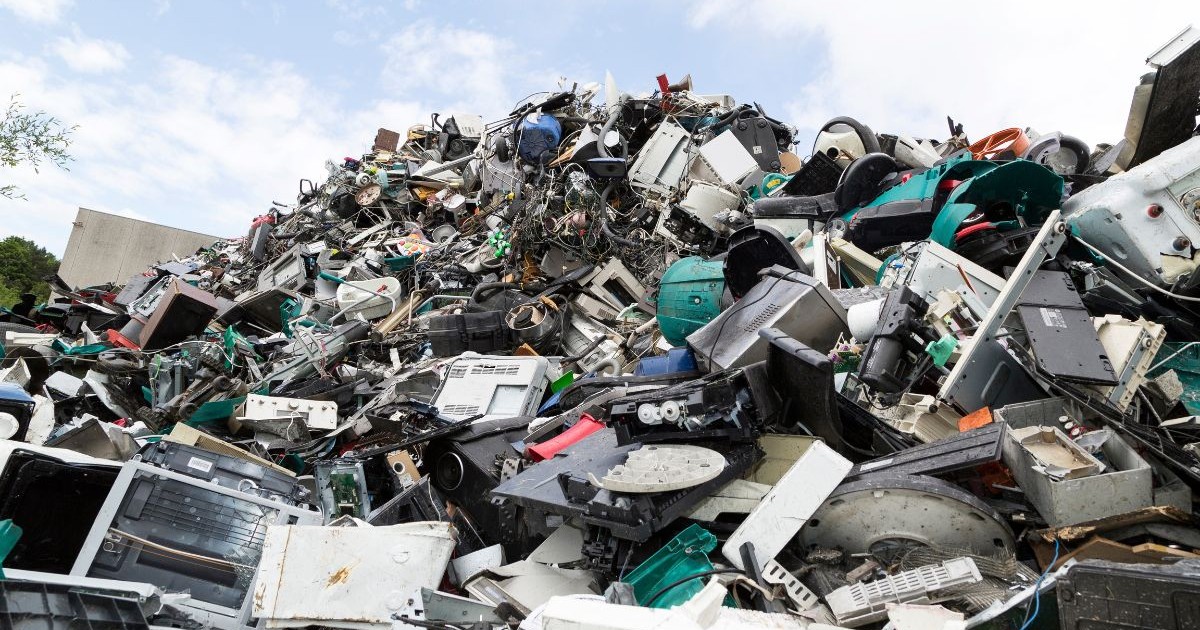 o grămadă uriașă de obiecte dezmembrate, compusă din numeroase componente din plastic și metal. Se disting carcase, cabluri, plăci, ecrane, rotoare, butoane și diverse piese de diferite forme și culori, toate împrăștiate haotic.