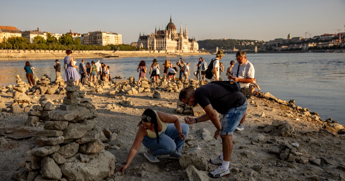 Turiștii și localnici din Budapesta, în timp ce se plimbă pe maul Dunării și adună pietre