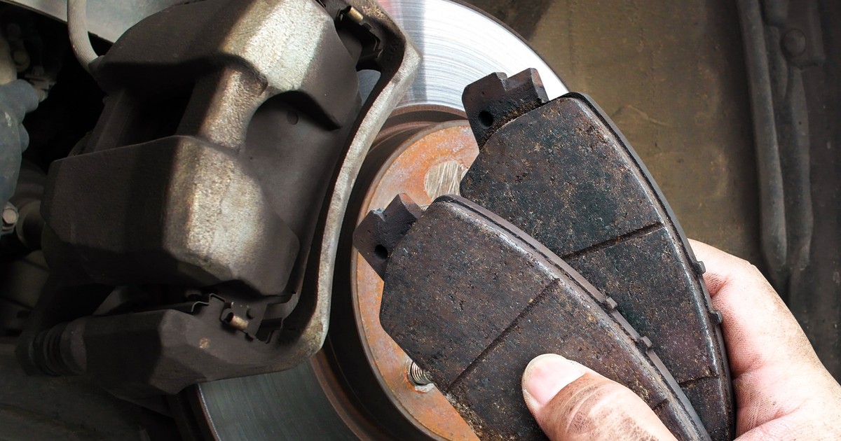 placute de frana auto prezentate de un mecanic, pe fundal disc de frana
