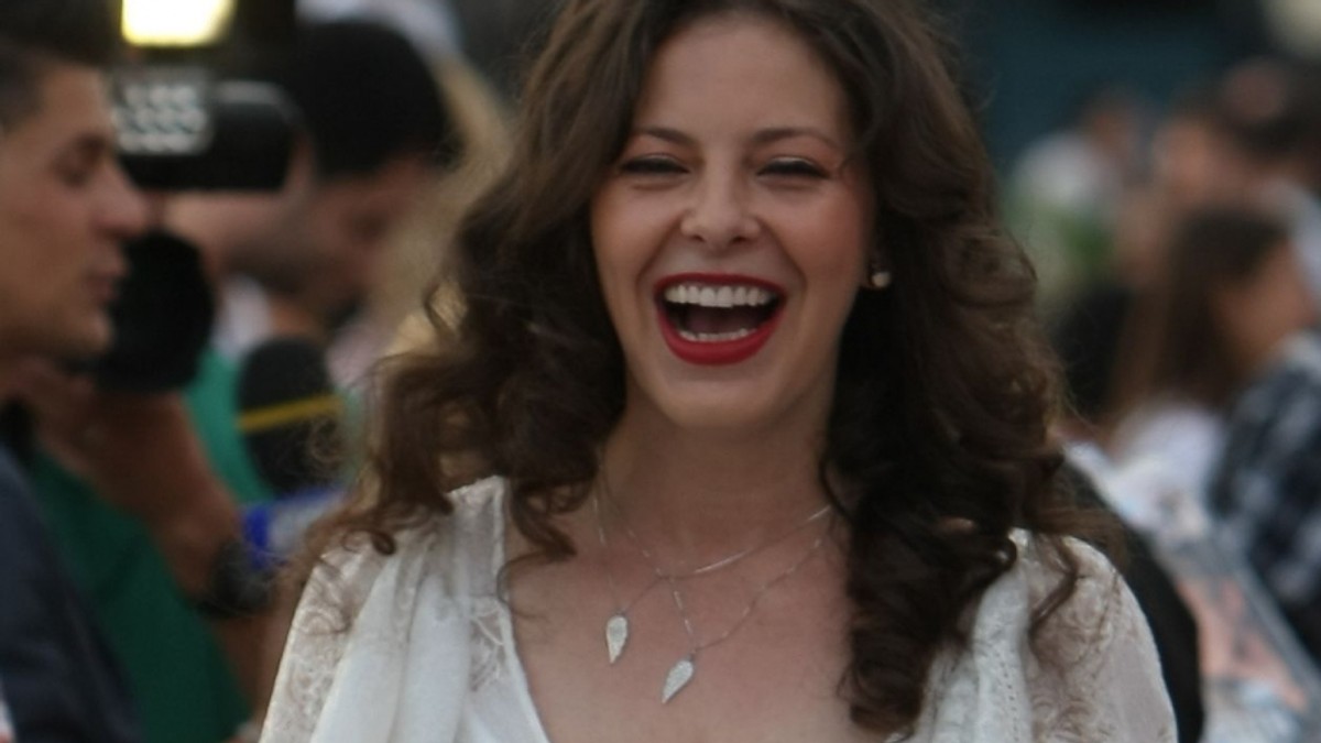 Rita Mureșan, îmbrăcată într-o rochie albă ca de mireasă, râde cu gura până la urechi