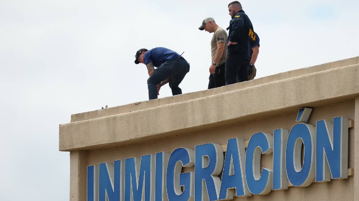 Polițiștii verifică acoperișul unei clădiri din apropierea locului împușcăturilor de la un birou al Imigrării și Vamei din SUA din Dallas. Pe clădire scrie mare Imigrare