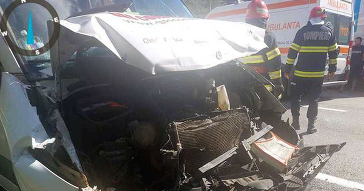 Un microbuz este lovit în plin în față, în dreapta lui se vede o mașină de ambulanță, pompieri SMURD și câțiva oameni care se uită, Caraș-Severin, 28 iulie 2025