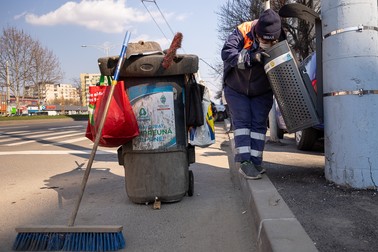 O lucrătoare de la Urban SA inspectează un coş de gunoi pe Bulevardul Iuliu Maniu
