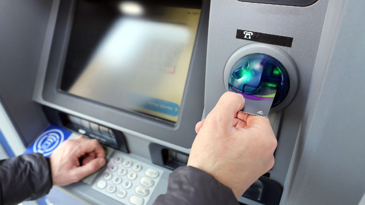 Un bărbat efectuează o tranzacție cu un card de credit la un bancomat