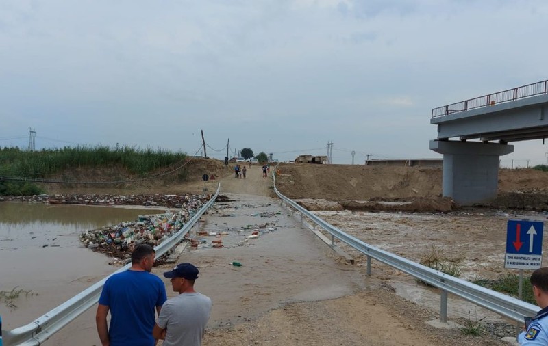 Rampele podului provizoriu de la Vadu Roşca, distruse în urma unei viituri. Tone de peturi și crengi blochează scurgerea apei
