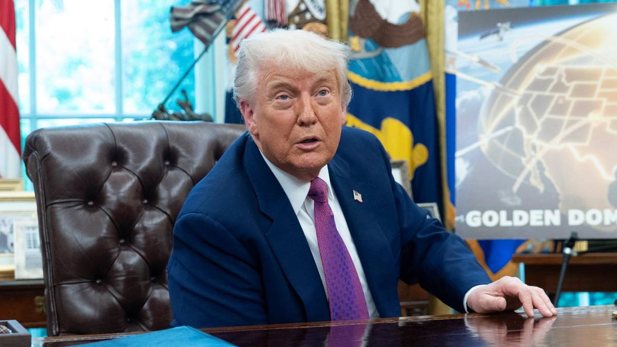 Donald Trump la masă în Biroul Oval de la Casa Albă, îmbrăcat la costum și purtând o cravată mov.
