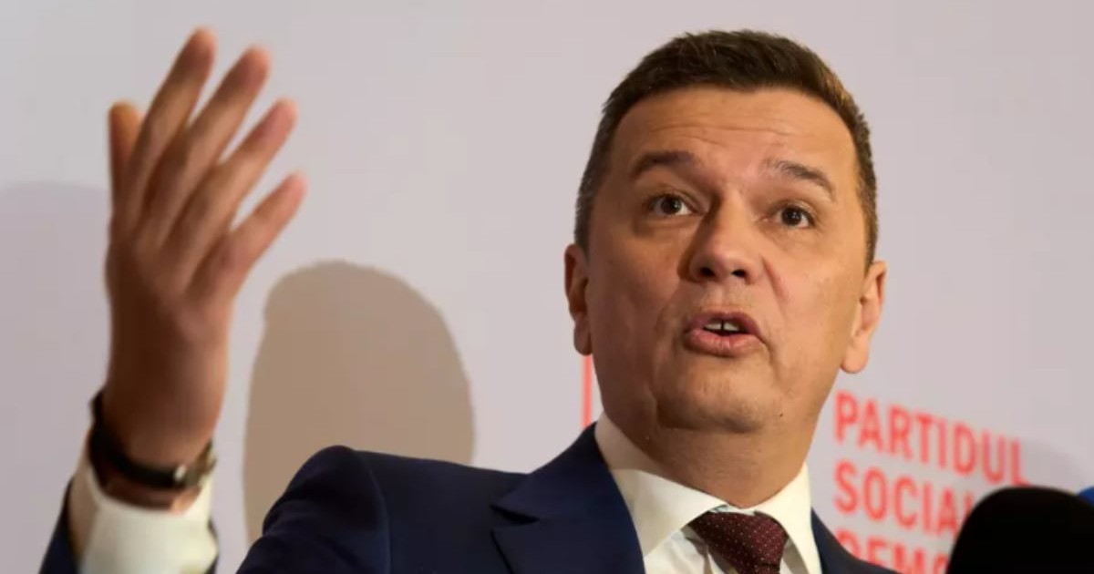 Sorin Grindeanu într-un costum negru în timp ce ține o mână ridicată