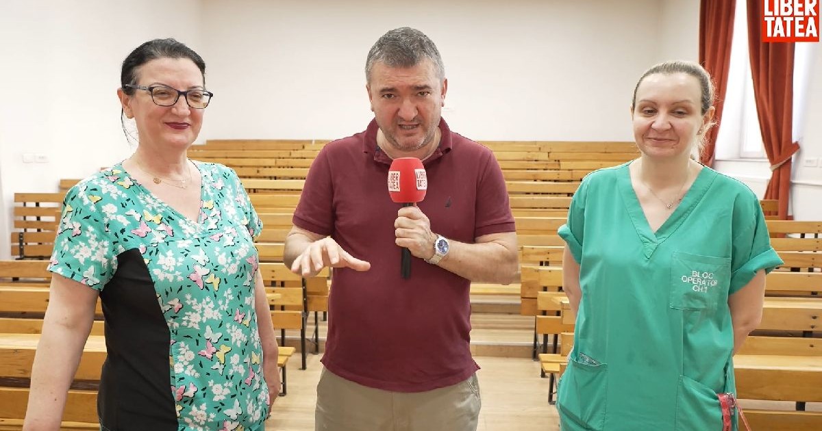 Un bărbat cu tricou vișiniu și microfon în mână, alături de două femei cu cămăși verzi, medici