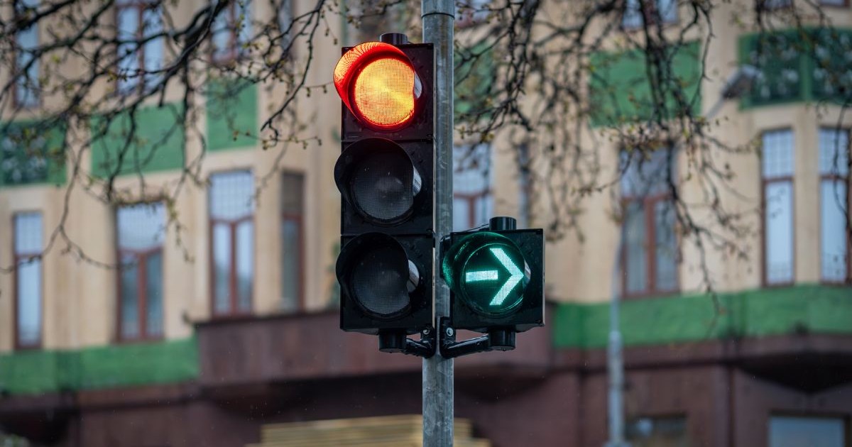 Semafor verde intermitent la dreapta și roșu pentru înainte, într-un oraș, cu o clădire pe fundal