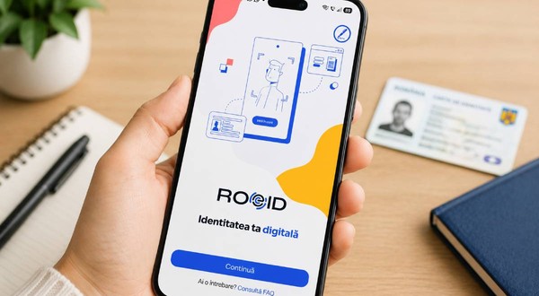 O mână ține un smartphone pe ecranul căruia este deschisă aplicația ROeID, cu mesajul „Identitatea ta digitală”. Pe masă, în fundal, se află o carte de identitate românească.