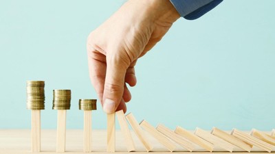 concept image of investing and banking. A businessman stops the domino effect from risking financial investment