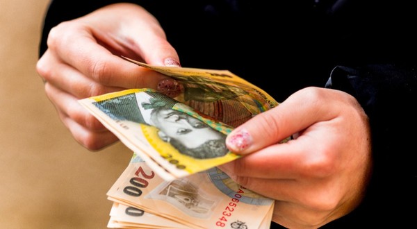 O tânără care numără mai multe bancnote de 200 de lei 