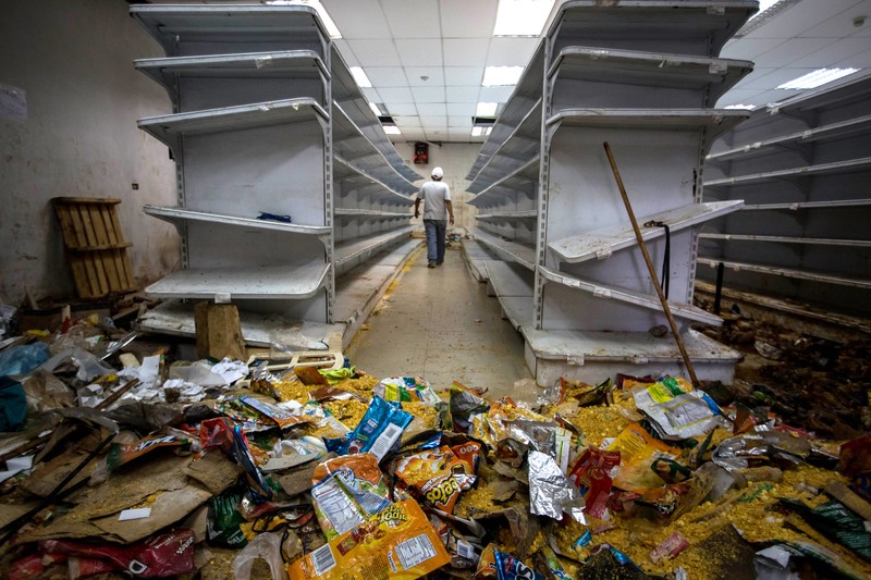Un bărbat merge pe culoarul unui magazin alimentar jefuit în Caracas, Venezuela, 21 aprilie 2017. Foto: EPA / MIGUEL GUTIERREZ