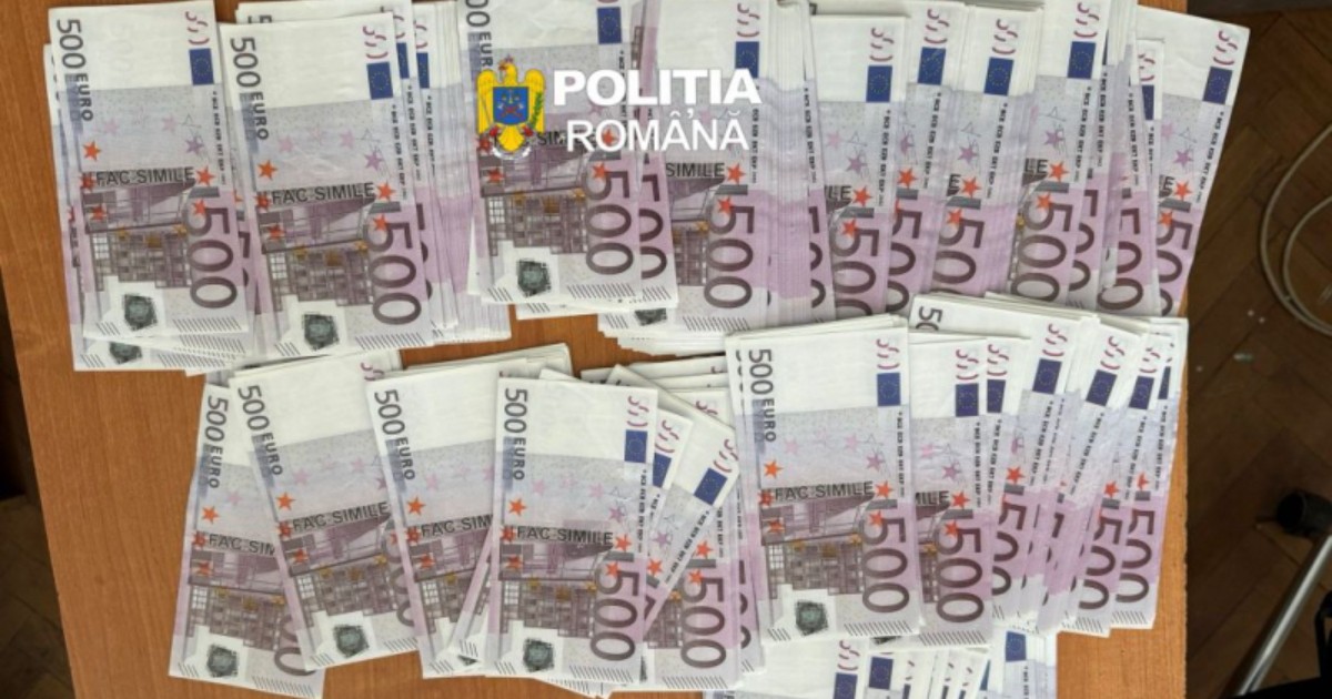 Pe o masă sunt expuse numeroase bancnote de 500 de euro contrafăcute, aranjate în teancuri, iar pe acestea se observă inscripția „FAC-SIMILE”. În centrul imaginii apare sigla Poliției Române, sugerând că bancnotele au fost confiscate în cadrul unei acțiuni a autorităților.