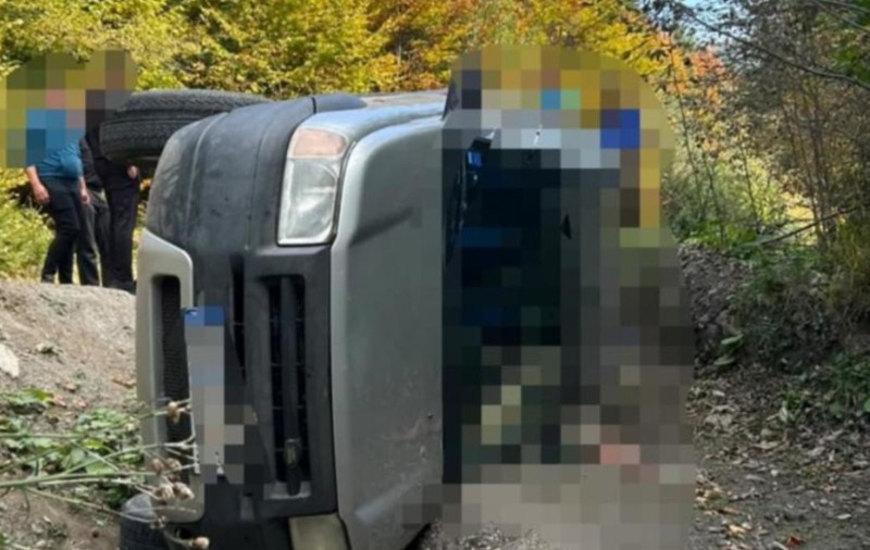 O mașină răsturnată pe drum forestier. Aceasta are numerele de înmatriculare și parbrizul blurate