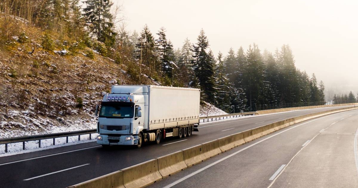 Camion - TIR alb, pe o sosea din Austria, se vede o zona cu brazi si zapada