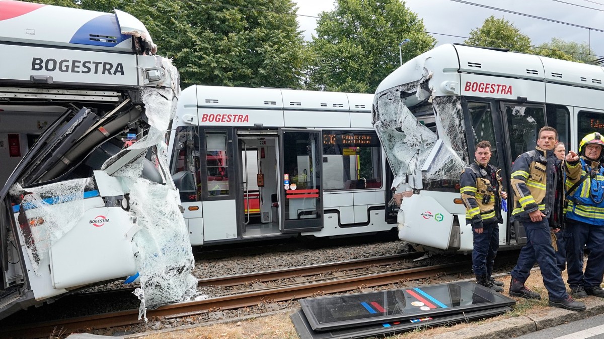 Două tramvaie care s-au ciocnit pe șine, într-un accident în Germania, pompierii stau lângă ele și așteaptă să fie ridicate