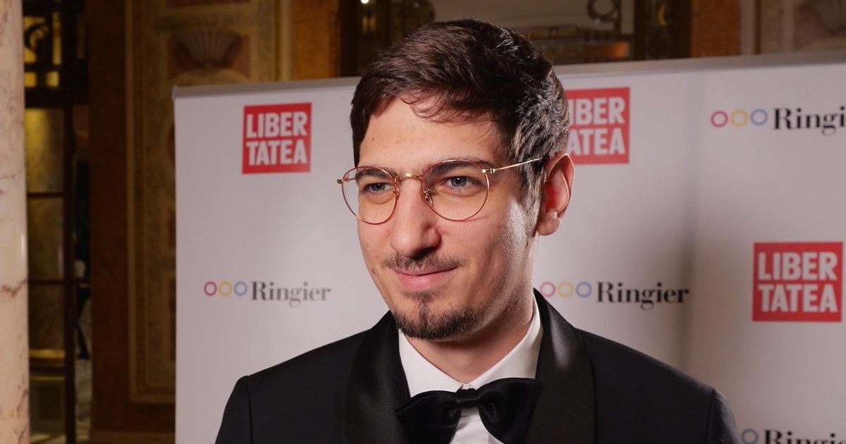 Matei Lucescu, fondatorul Bere Grivița, îmbrăcat în costum negru, cu cămașă albă și papion negru, iar pe fundal un panou cu logo-urile Libertatea și Ringier