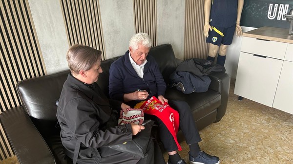 Mircea Dridea semnează pe un fular cu însemnele lui FC Liverpool