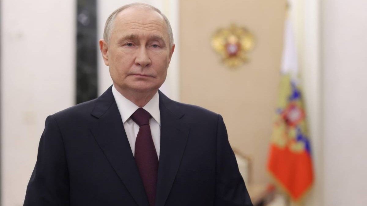 Liderul rus Vladimir Putin, in costum negru, cravata maro si camasa alba, cu steagul si stema Rusiei in fundal, neclare, 10 noiembrie 2025, Moscova