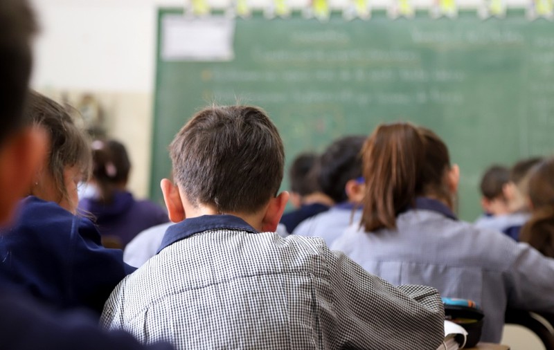 Elevi care stau în bănci, în clasă