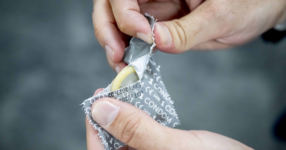 Un bărbat ruoe folia unui prezervativ