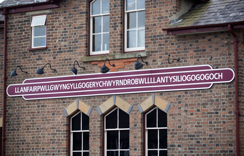 Llanfairpwllgwyngyllgogerychwyrndrobwllllantysiliogogogoch is a large village and community on the island of Anglesey in Wales, situated on the Menai Strait next to the Britannia Bridge and across the strait from Bangor. This village has the longest place name in Europe and one of the longest place names in the world. The short form of the village's name is Llanfairpwllgwyngyll, also spelled Llanfair Pwllgwyngyll. It is commonly known as Llanfair PG or Llanfairpwll. According to the 2001 census, the population of the community is 3, 040, [1] 76% of whom speak Welsh fluently; the highest percentage of speakers is in the 10–14 age group, where 97. 1% are able to speak Welsh. [citation needed] It is the fifth largest settlement on the island by population. Visitors stop at the railway station to be photographed next to the station sign, visit the nearby Visitors' Centre, or have 'passports' stamped at a local shop. Another tourist attraction is the nearby Marquess of Anglesey's Column, which at a height of 27 metres (89 ft) offers views over Anglesey and the Menai Strait. Designed by Thomas Harrison, the monument celebrates the heroism of Henry Paget, 1st Marquess of Anglesey at the Battle of Waterloo.,Image: 132678816, License: Rights-managed, Restrictions: , Model Release: no