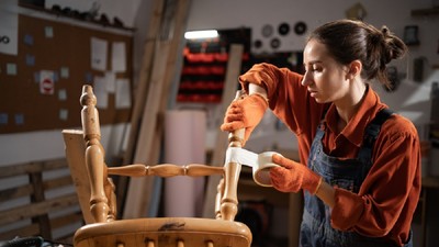 10 moduri neobișnuite de a folosi banda adezivă - O tânără se află într-un atelier unde repară cu banda adezivă piciorul unui scaun