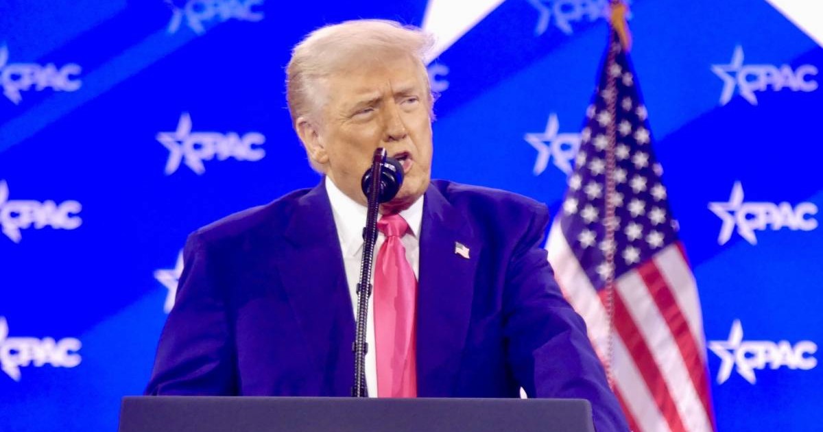 presedinte statele unite donald trump in timpul unui discurs, in spatele lui este steagul sua