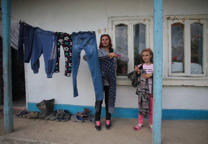Luiza, 8 ani, îşi ajută mama la strâns rufele de pe prispa casei bunicilor