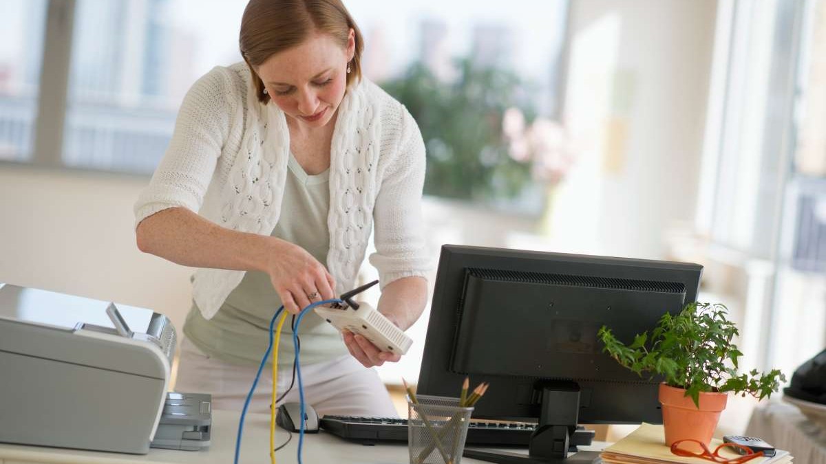 O femeie lucrează la instalarea unui router la biroul de acasă.