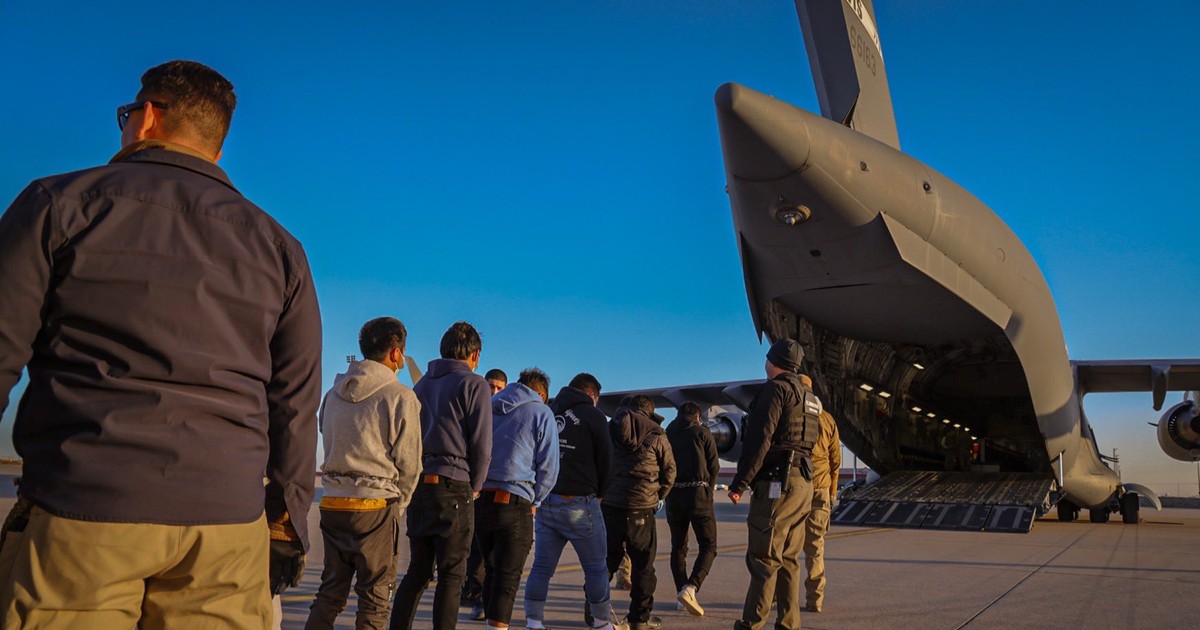 Imagine cu mexicani încătușați conduși la bordul unui avion militar american.
