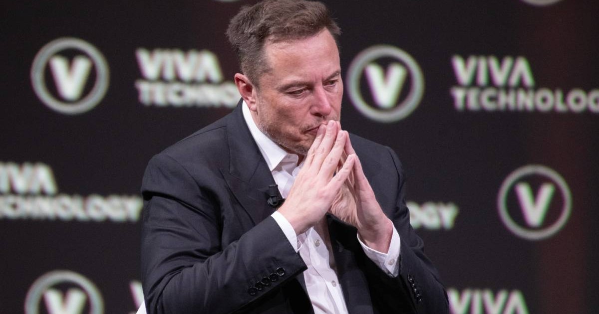 elon musk imbracat la costum in timpul unui interviu tine mainile impreunate ridicate la barbie
