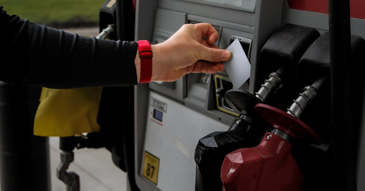 o persoană care folosește un card de credit la un cititor de plăți de la o pompă de benzină a unei stații de alimentare
