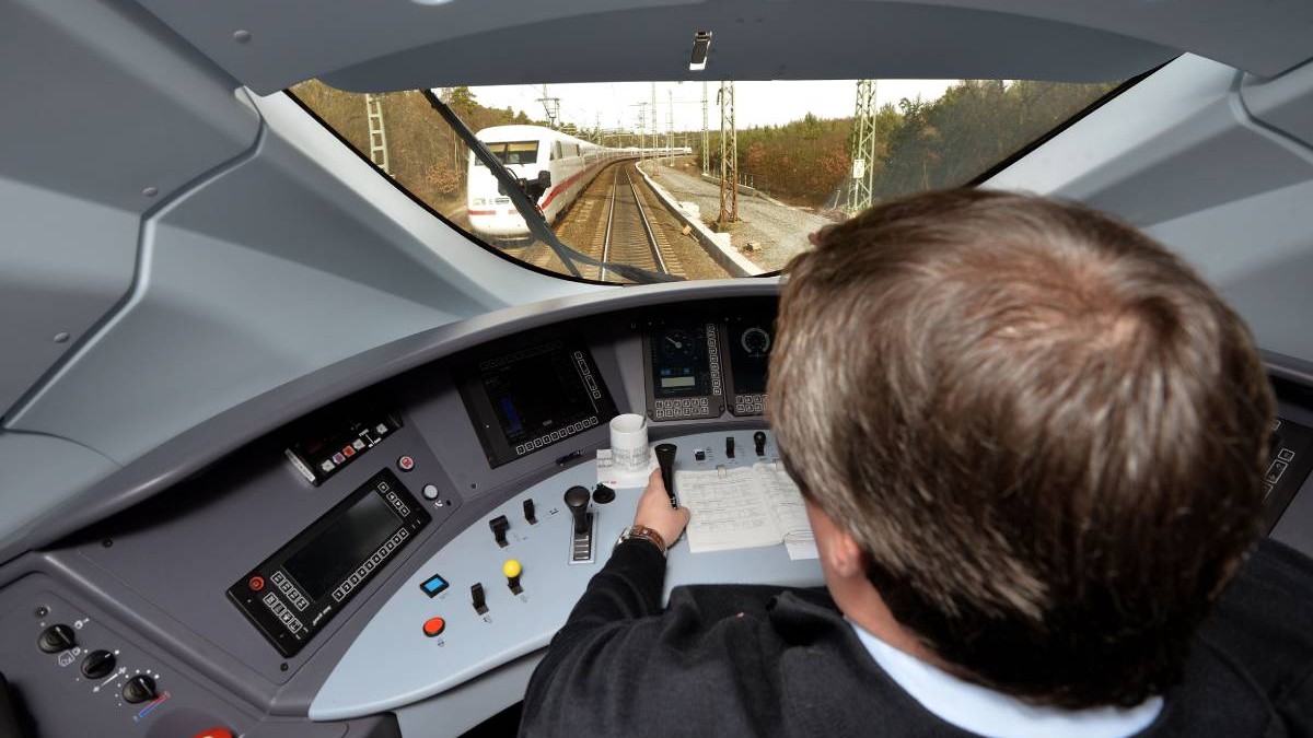 Mecanic de tren, in cabina, conduce trenul, are niste notite pe bord, din fata se vede cum vine un alt tren alb