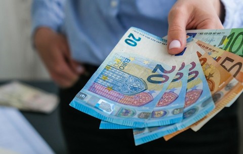 O femeie ținând în mână bancnote de euro într-un birou