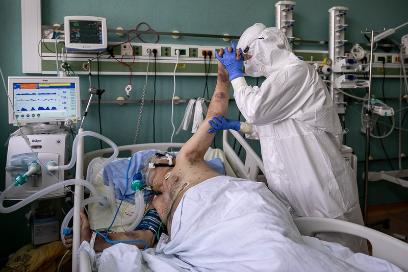 Un kinetoterapeut mişcă braţul unui pacient, pentru a stimula circulaţia