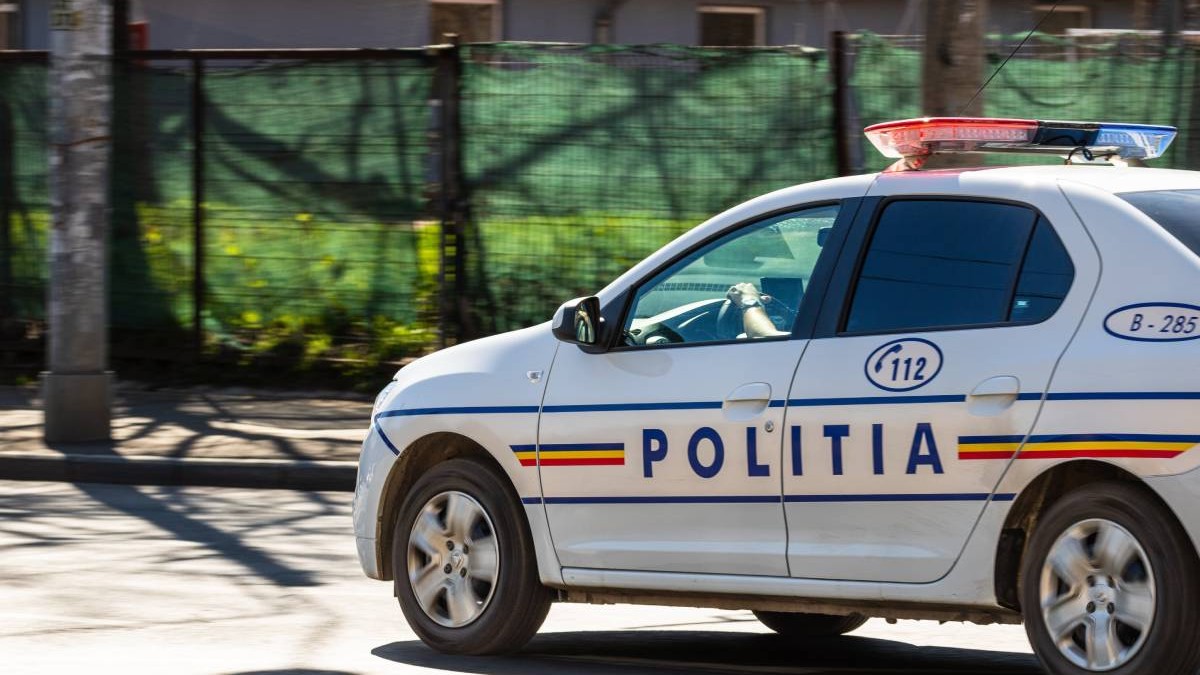 O mașină de Poliție, mergând pe stradă spre locul unei intervenții în București, într-o zonă în care se află o clădire în construcție