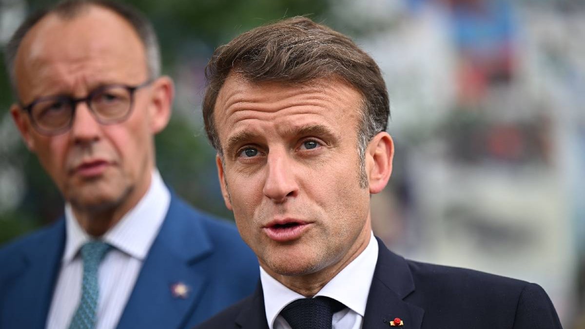 Președintele Franței, Macron, în prim plan și cancelarul german, Merz, în spatele său, privindu-l cu îngrijorare