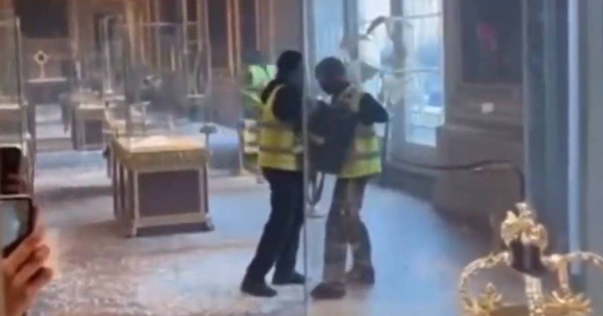 Imaginea surprinde doi bărbati cu veste galbene si cagule negre pe cap lângă vitrine, carand ceva, în Galeria Apollon din Muzeul Luvru, 19 octombrie 2025