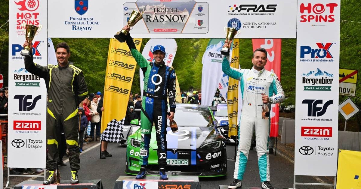Podiumul competiției Trofeul Râșnov 2025. Pe locul 1 este Dominic Marcu, îmbrăcat în combinezon albastru, ținând trofeul ridicat, în fața unei mașini electrice Tesla Model S. Pe locurile 2 și 3 se află ceilalți doi concurenți de pe podium.